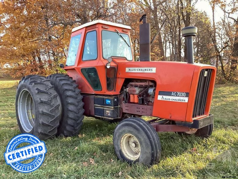 A red Stampede tractor ready for auction, sitting in a grassy field